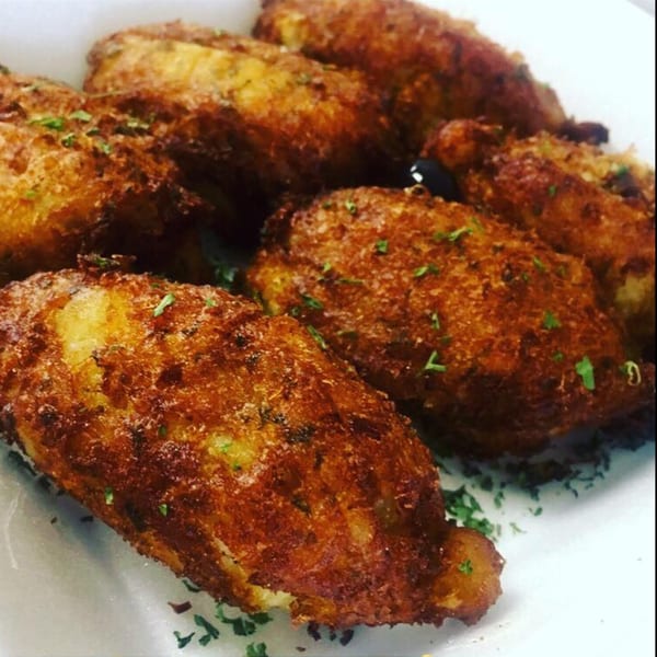 A close-up of several golden-brown, crispy Portuguese codfish cakes, garnished with fresh parsley.