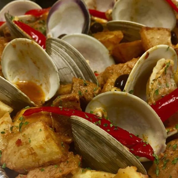 Portuguese clams with red peppers, potatoes, and olives, garnished with parsley.
