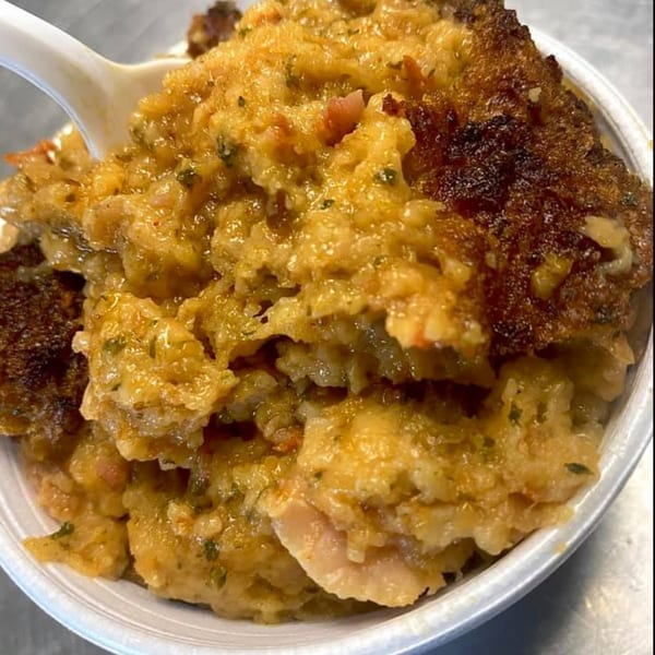 Close-up of a white spoon in a bowl of Portuguese seafood rice with a crispy top.