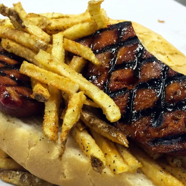 Grilled Portuguese sausage with crisscross char marks and golden french fries on a bun.